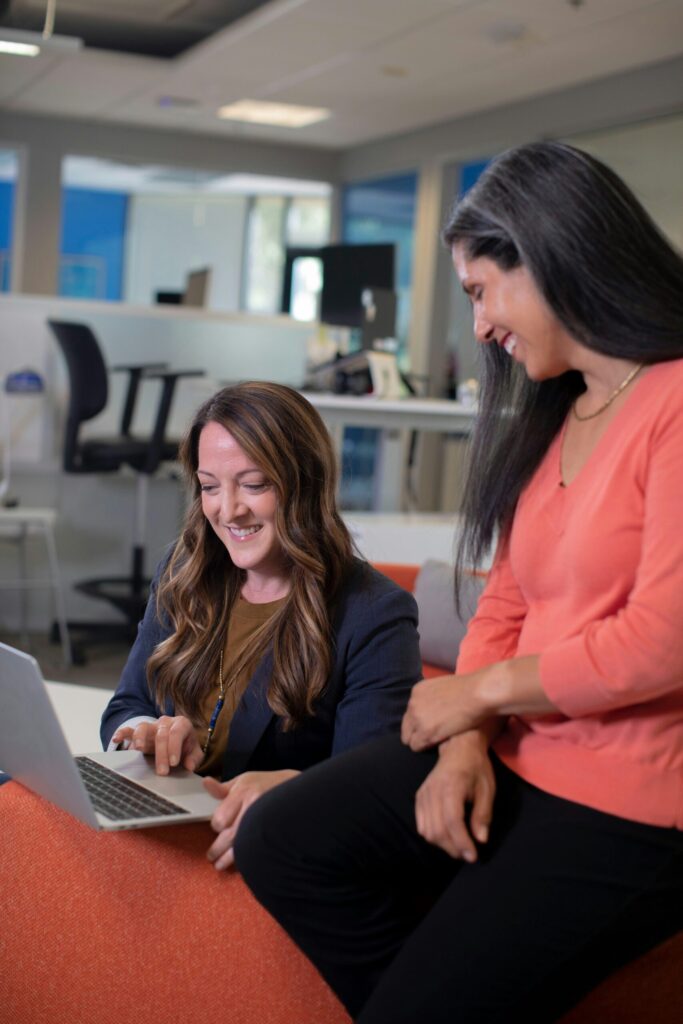 Two businesswomen discussing a concept in front of a shared computer screen.